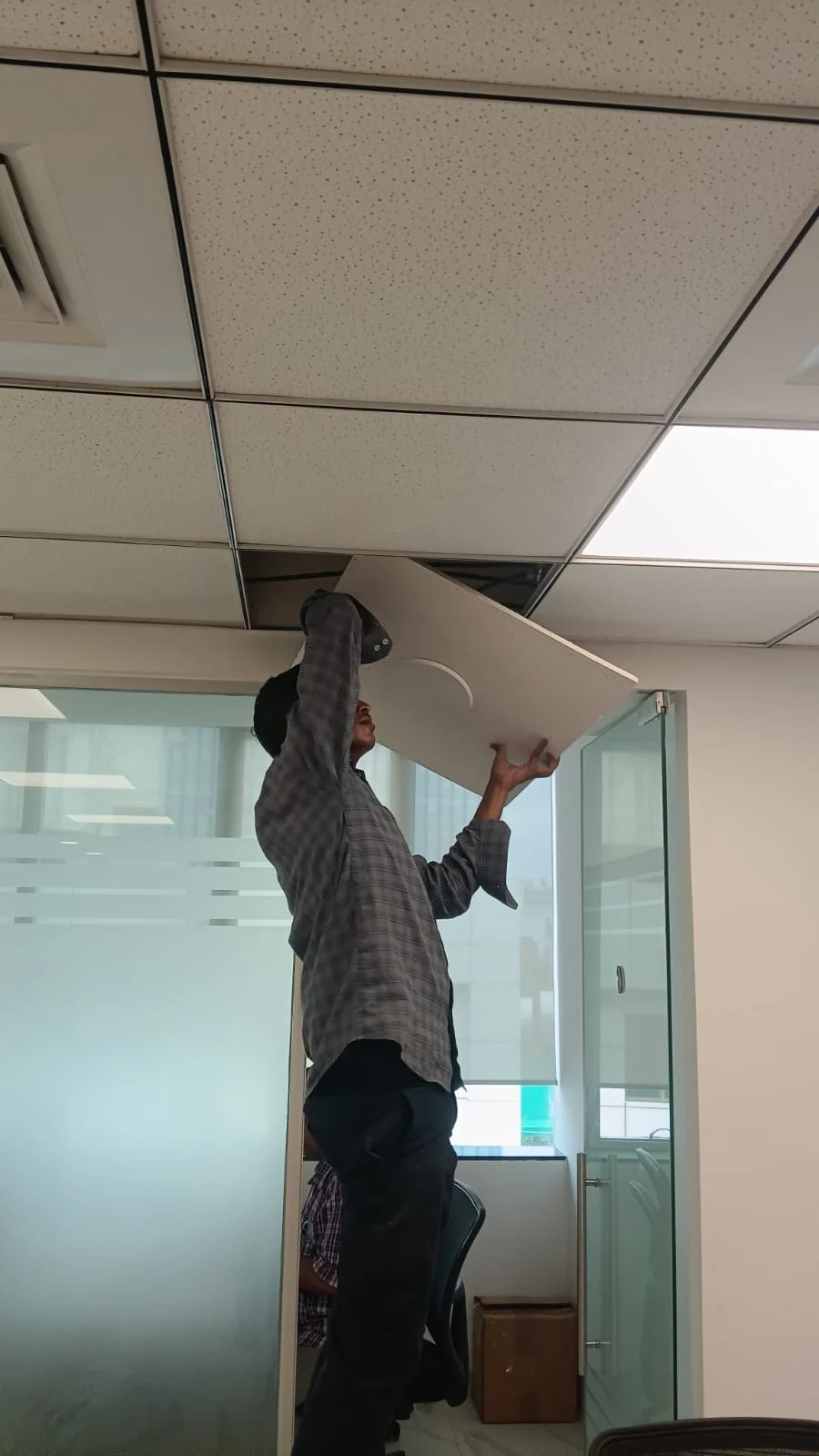 Technician installing an antenna within a false ceiling