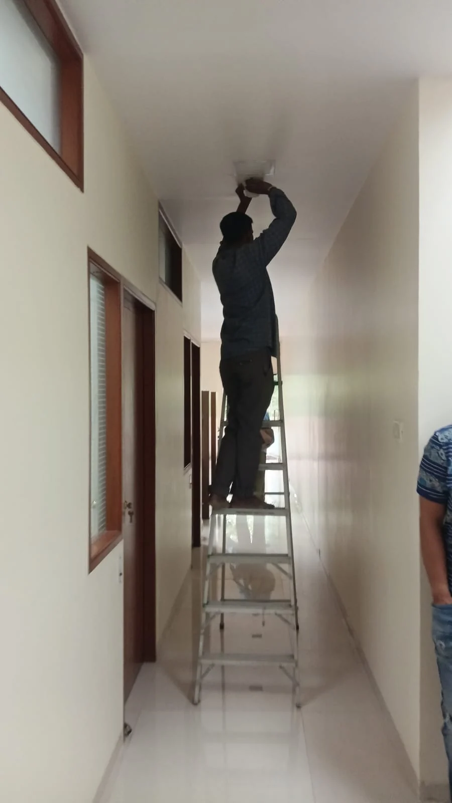 Technician installing a mobile signal antenna in a corridor